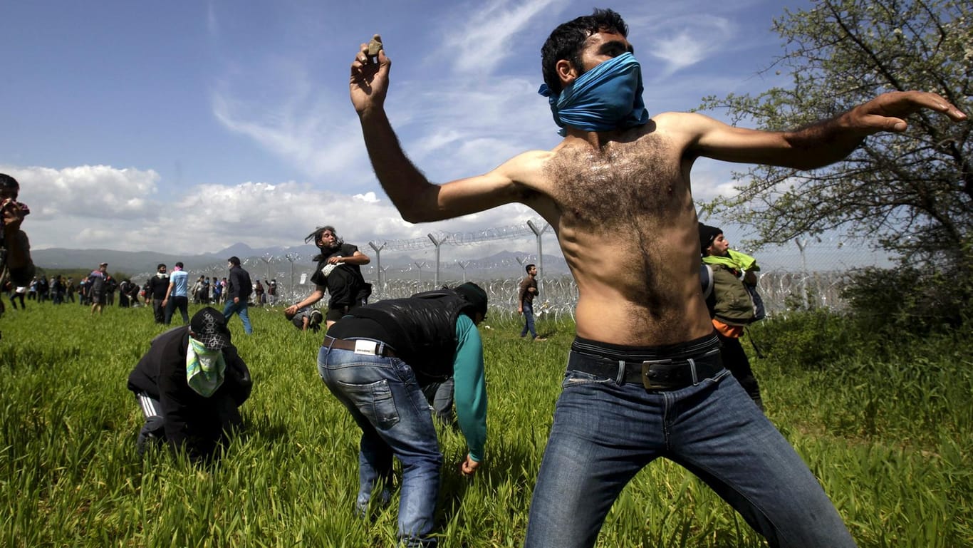 Flüchtlinge werfen bei Zusammenstößen mit der Polizei an der Grenze zu Mazedonien Steine.