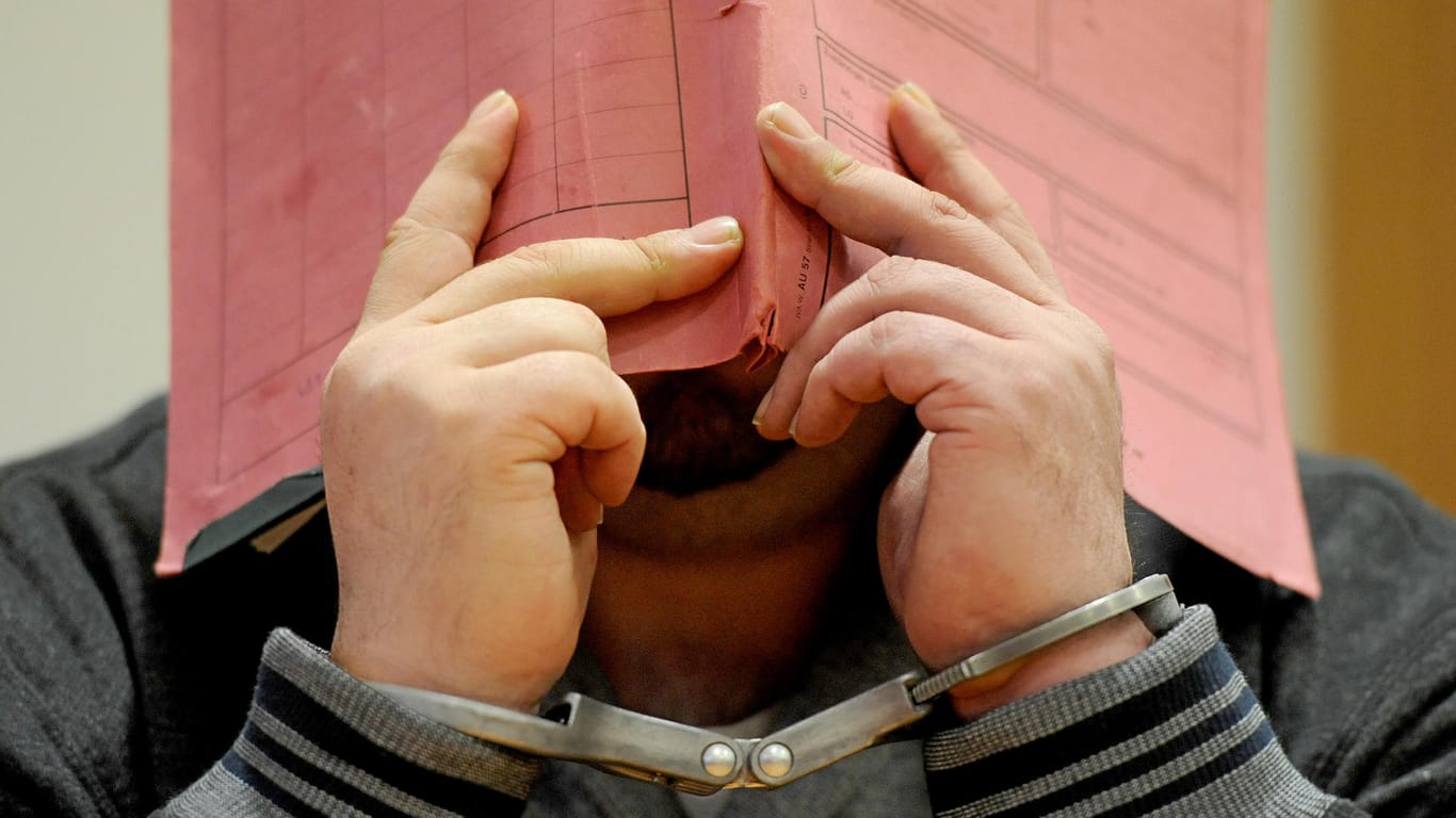 Der ehemalige Krankenpfleger Niels H. versteckt im Landgericht in Oldenburg sein Gesicht hinter einem Aktendeckel.