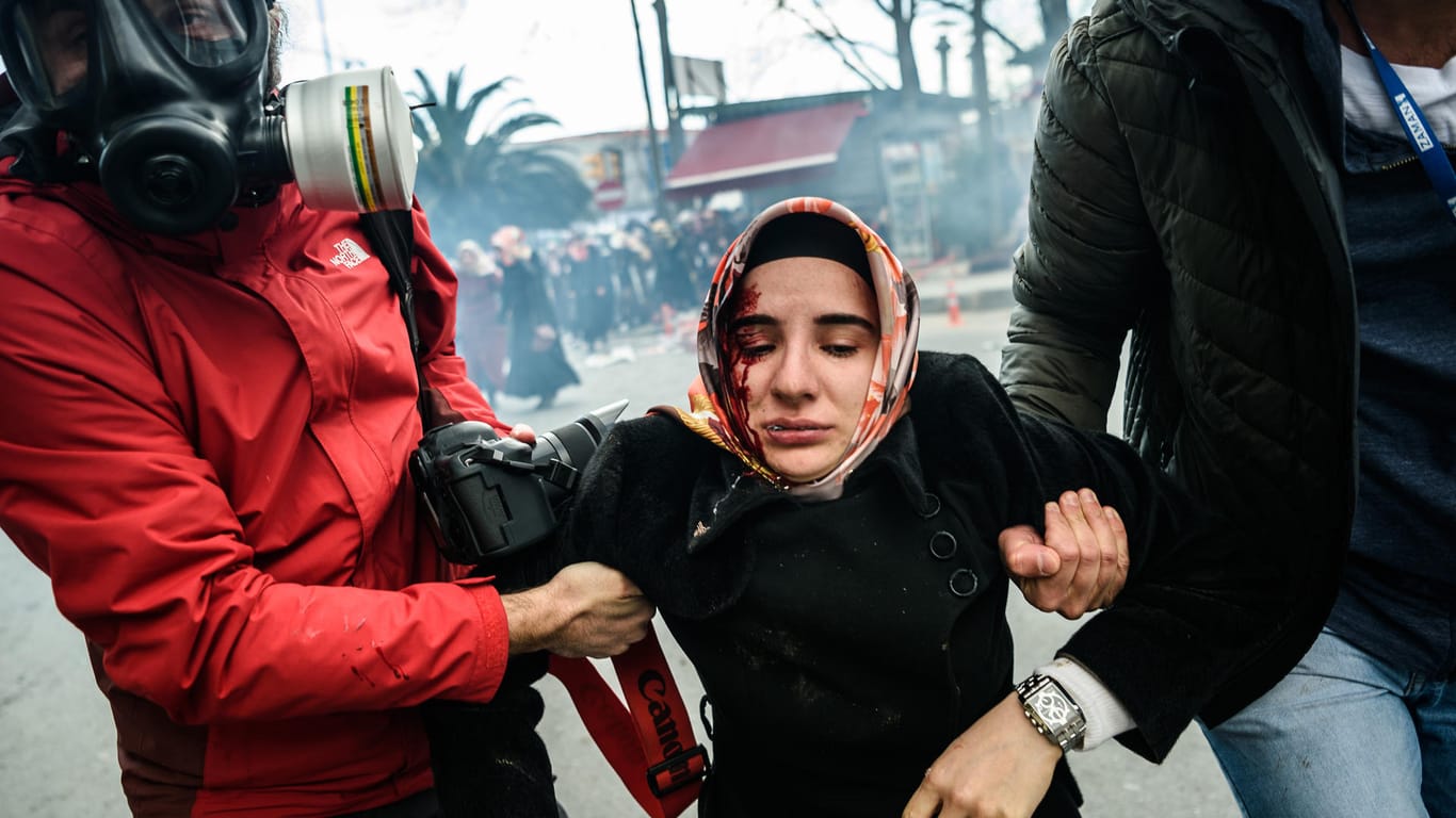 Journalisten bringen eine verletzte Frau vor dem Tränengas der Polizei bei Ausschreitungen vor der Redaktion der Zeitung Zaman in Sicherheit. Die Redaktion wurde zuvor von Sicherheitskräften gestürmt.