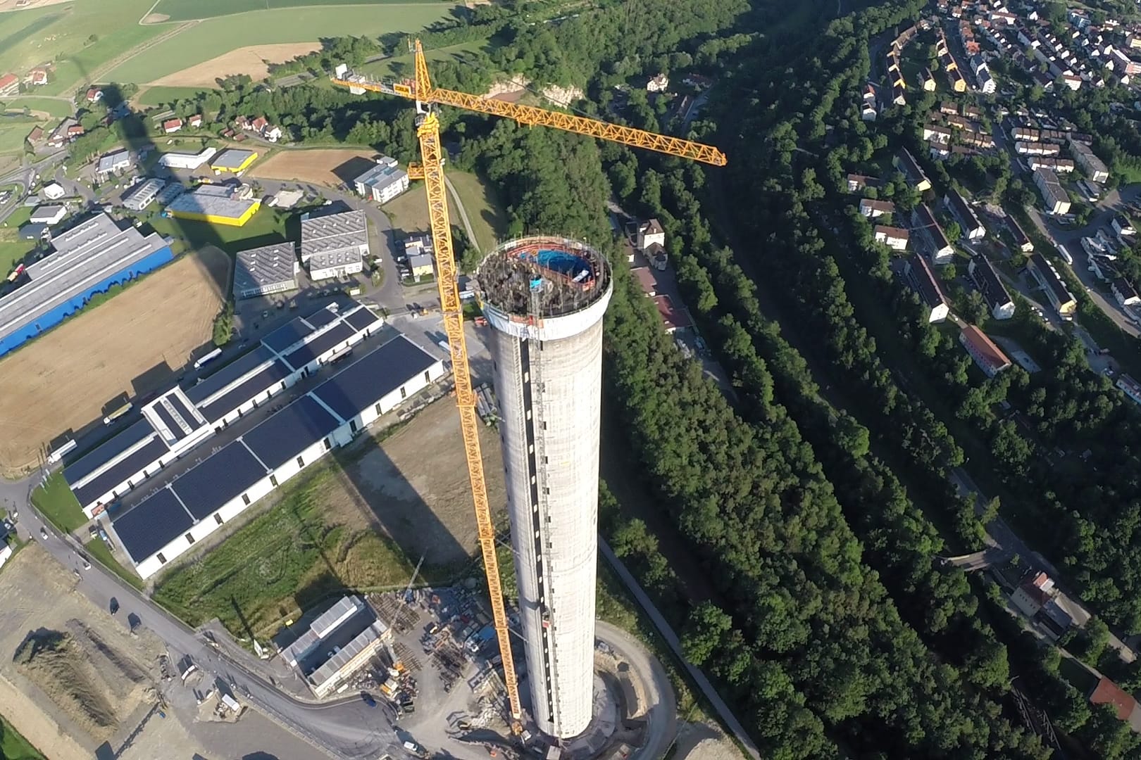 Der Testturm für Aufzüge ragt neben dem Städtchen Rottweil aus der beschaulichen Landschaft. Auf dem Bild sieht man noch den Hochhauskran, der schwere Teile auf den Turm hievt.