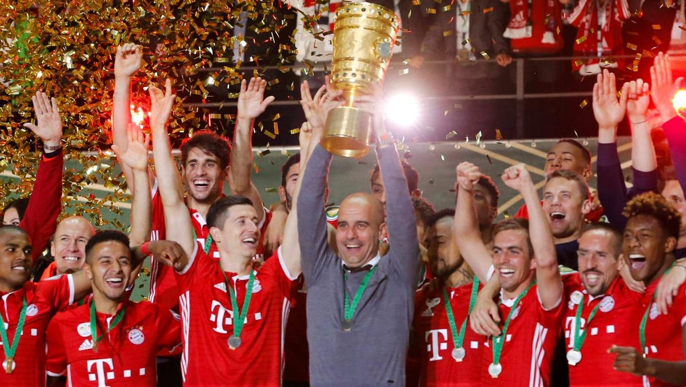 Bayern-Trainer Pep Guardiola hält den Pokal in seinen Händen.