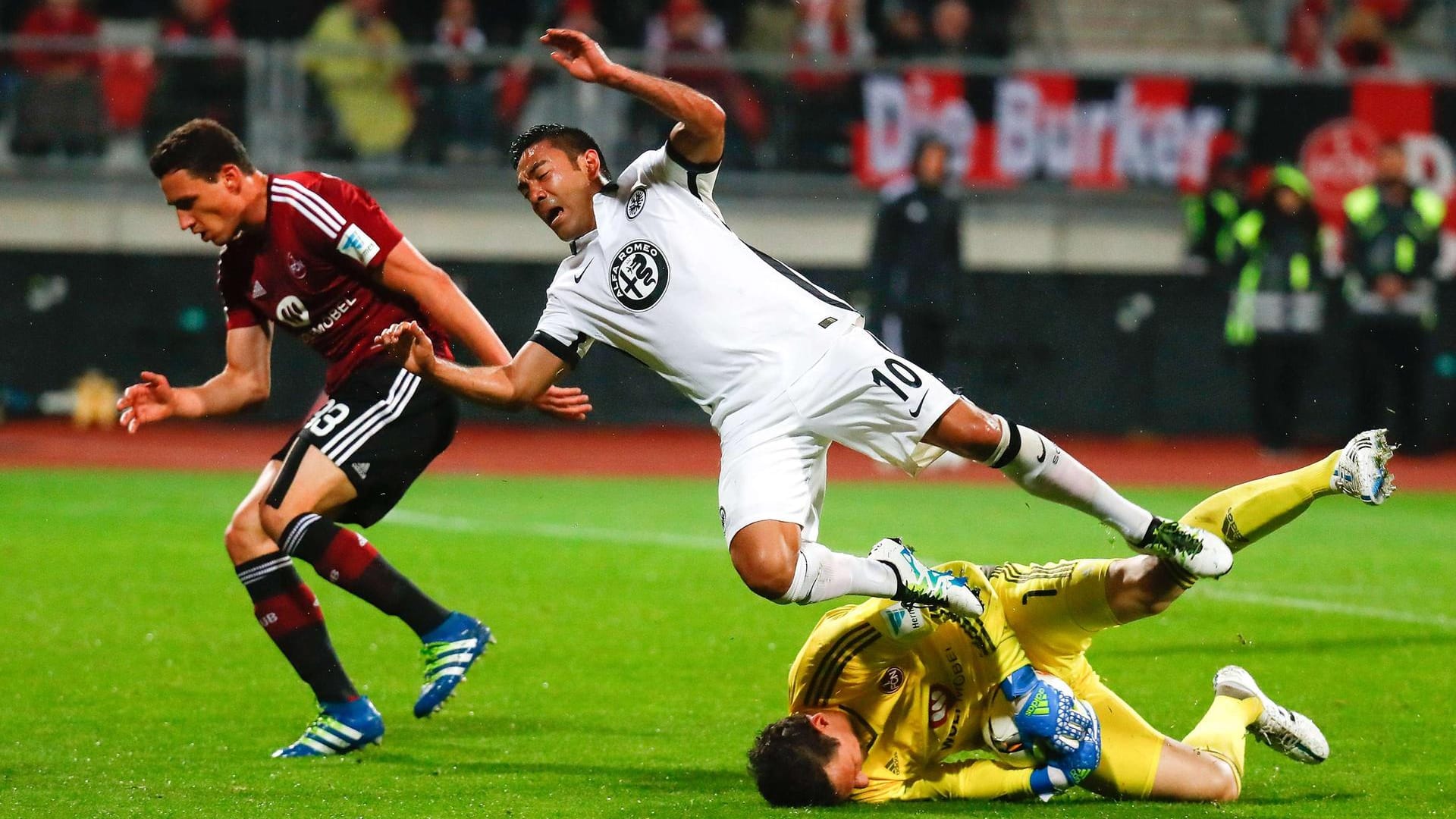 Marco Fabian von Eintracht Frankfurt fällt über den Nürnberger Torhüter Raphael Schäfer.