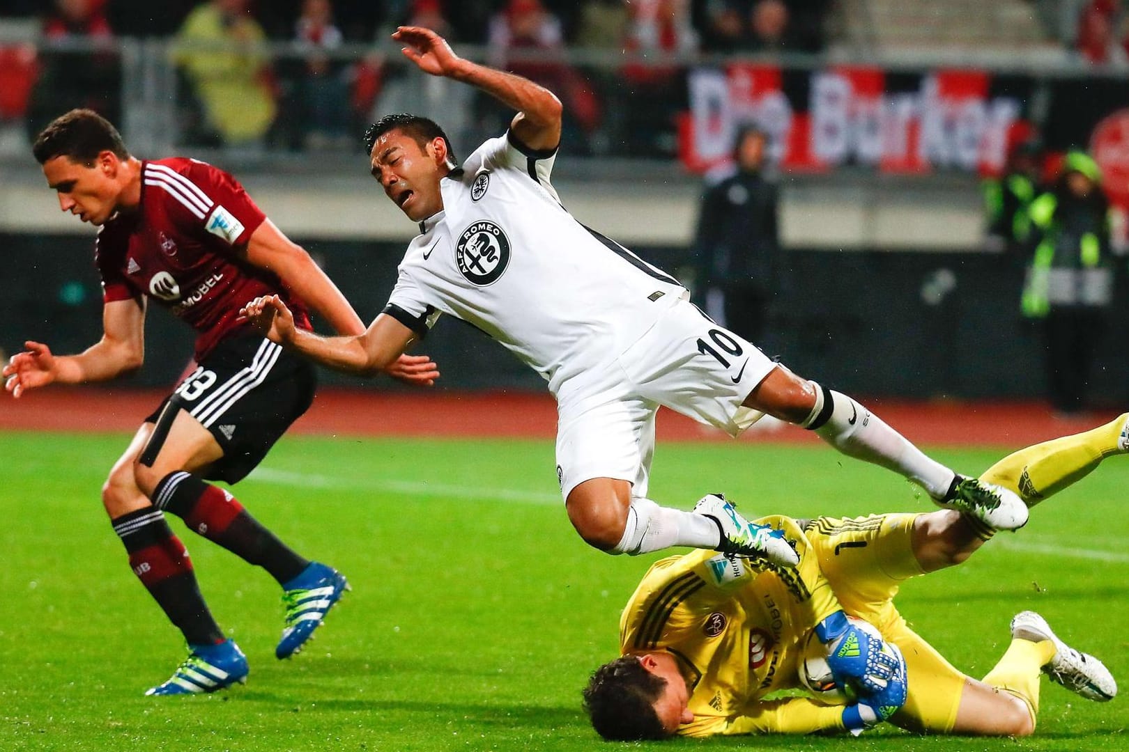 Marco Fabian von Eintracht Frankfurt fällt über den Nürnberger Torhüter Raphael Schäfer.