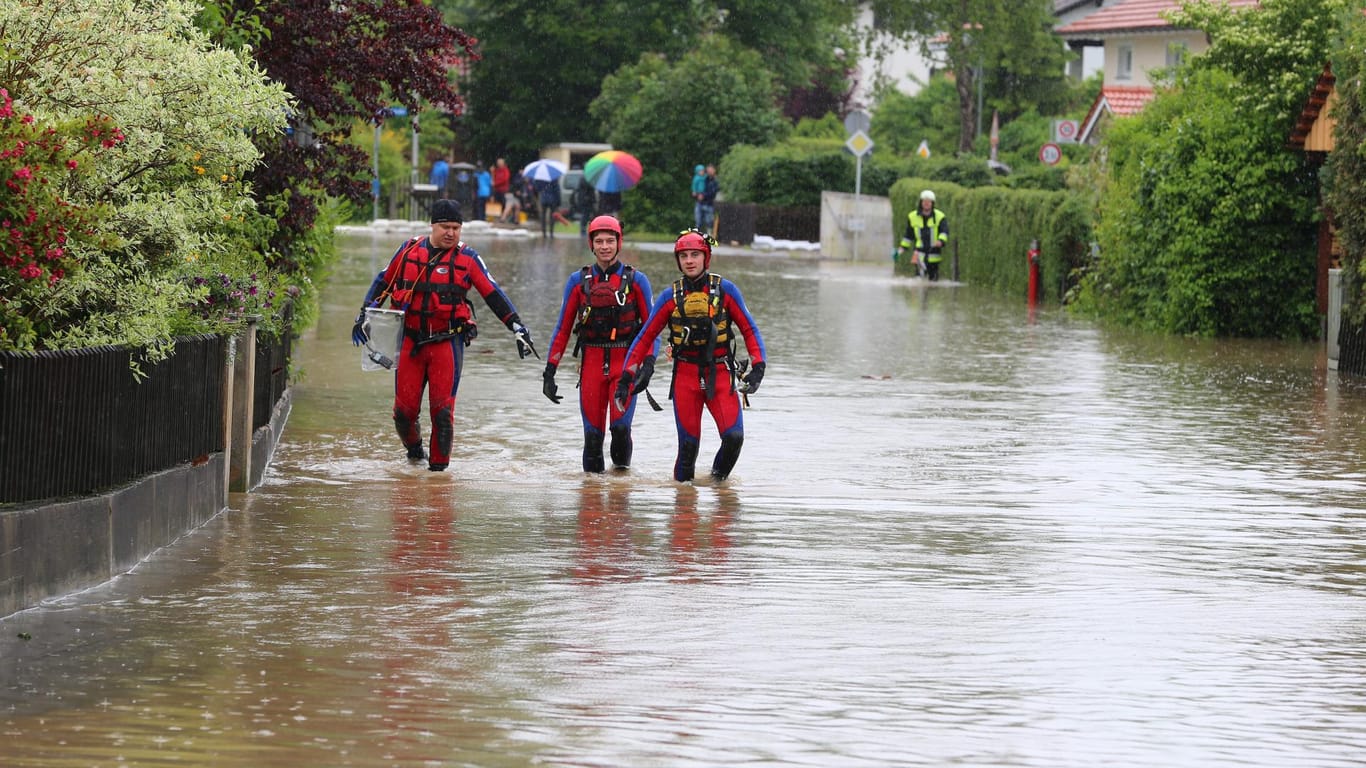 Einsatzkräfte in Polling auf einer überfluteten Straßen.