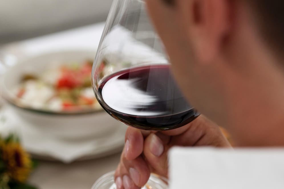 Ein Mann trinkt aus einem Rotweinglas