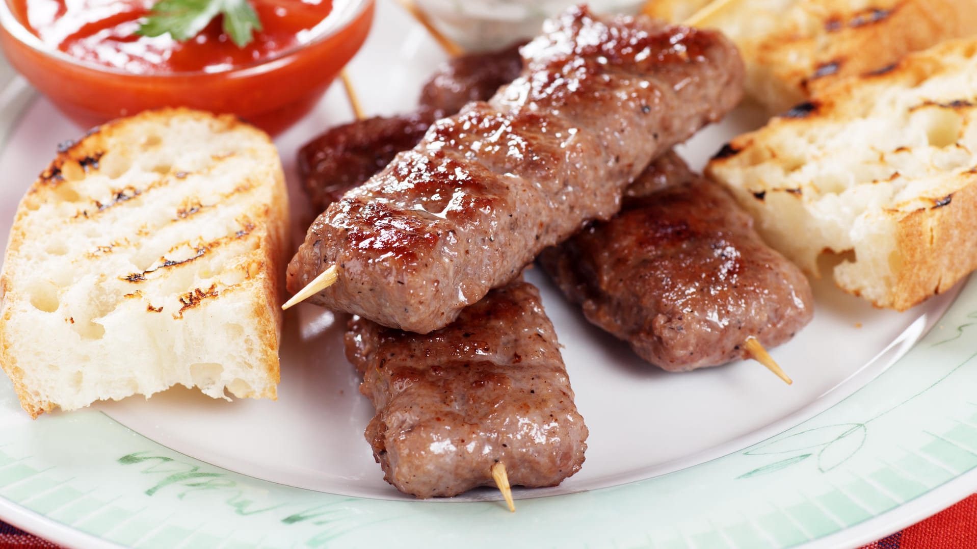 Zu den gegrillten Hackfleischspießen passen als Beilage bestens Baguette und Dips.