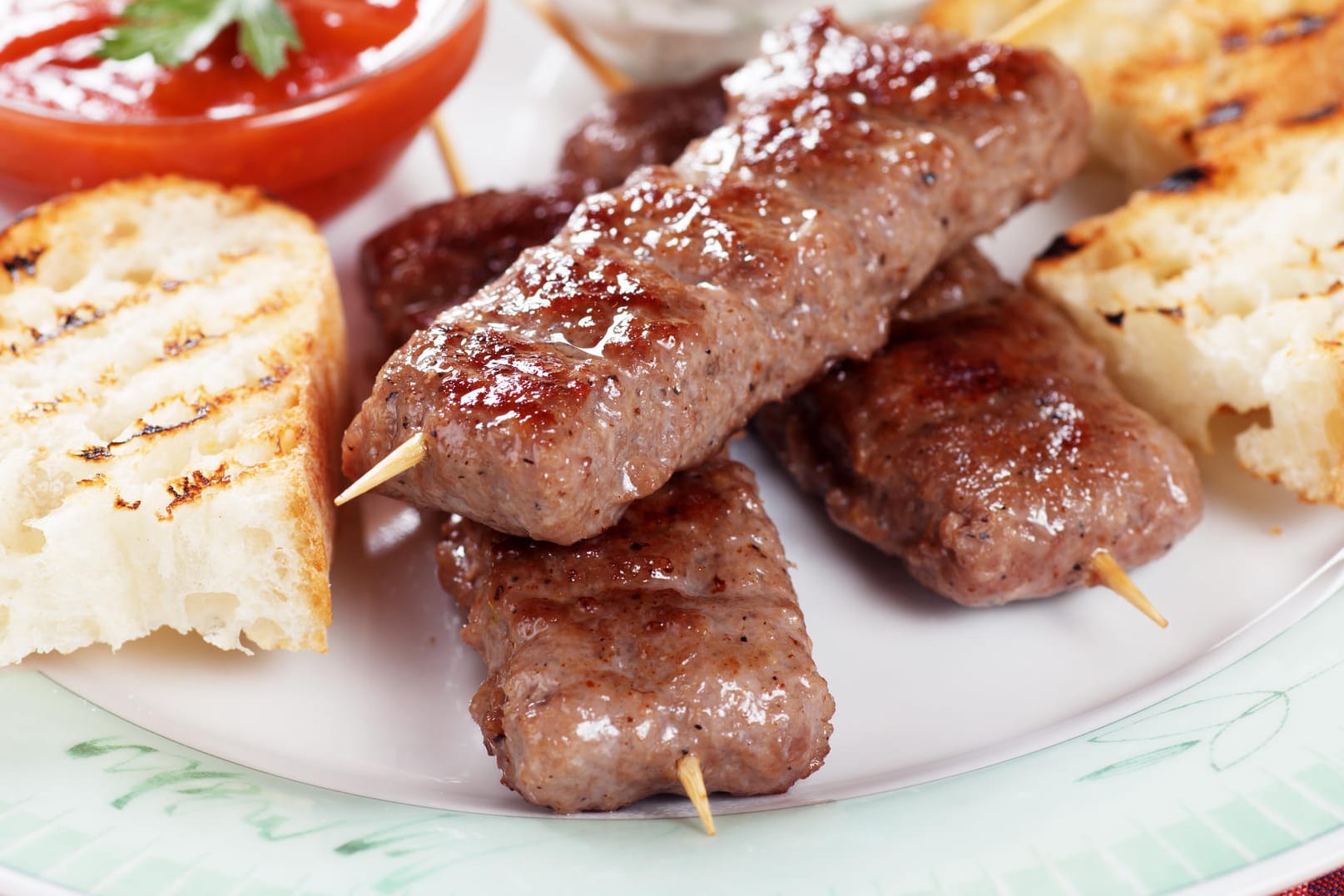 Zu den gegrillten Hackfleischspießen passen als Beilage bestens Baguette und Dips.