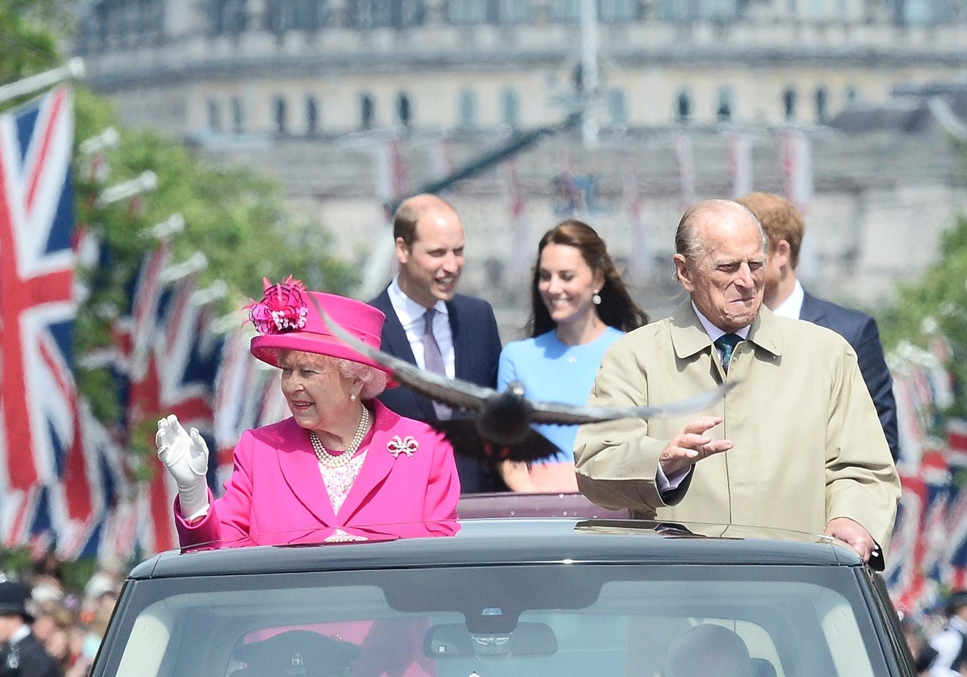 Queen Elizabeth II. und ihr Gatte fahren vorweg. Im zweiten Wagen steht das königliche Dreiergespann: Prinz William, Herzogin Kate und Prinz Harry.