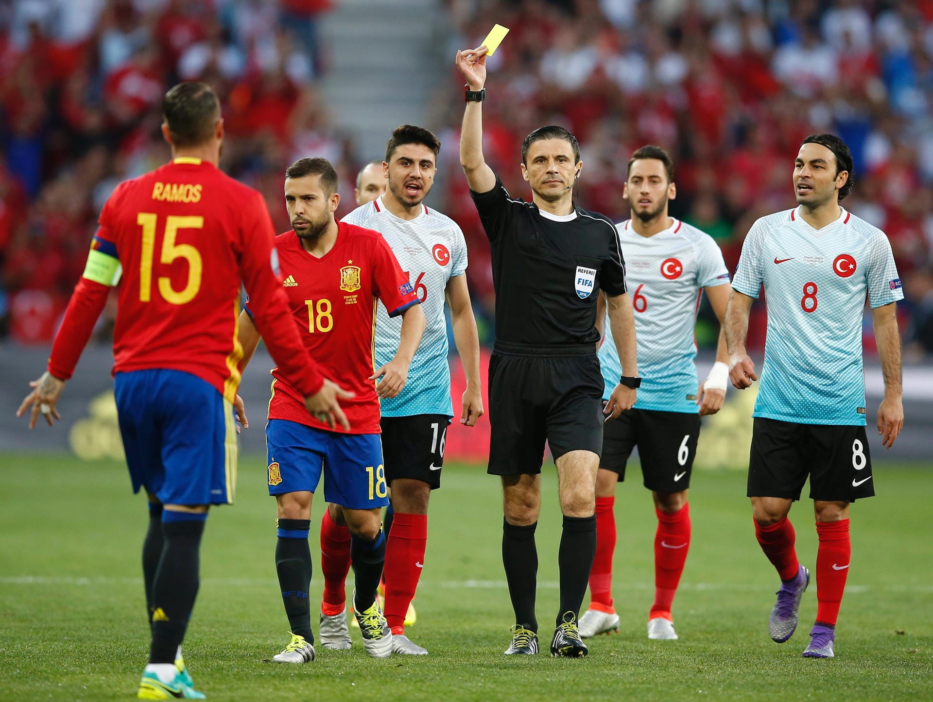 Sergio Ramos (li.) wird von Schiedsrichter Milorad Mazic aus Serbien bereits Sekunden nach Anpfiff der Partie verwarnt. Spaniens Kapitän hatte Burak Yilmaz im Mittelfeld zu Boden gecheckt.