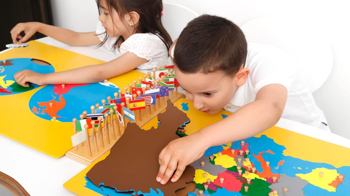 Kinder einer Montessori-Schule arbeiten selbständig mit Geografie-Material. In Montessori-Schulen werden Zeugnisse häufig als individueller Text formuliert.