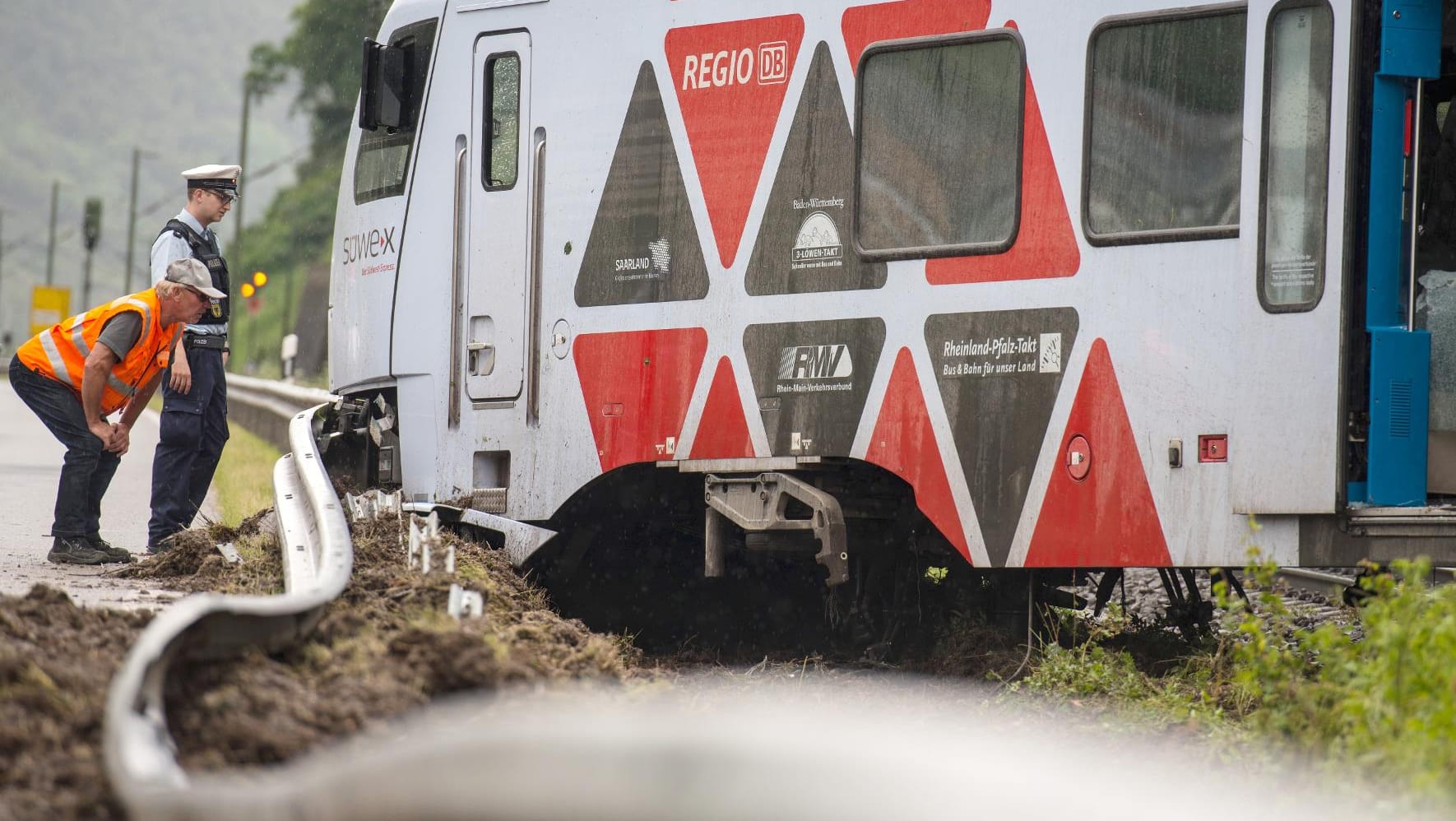 Ein Bahnmitarbeiter und ein Polizist inspizieren den entgleisten Regionalexpress RE 4251.