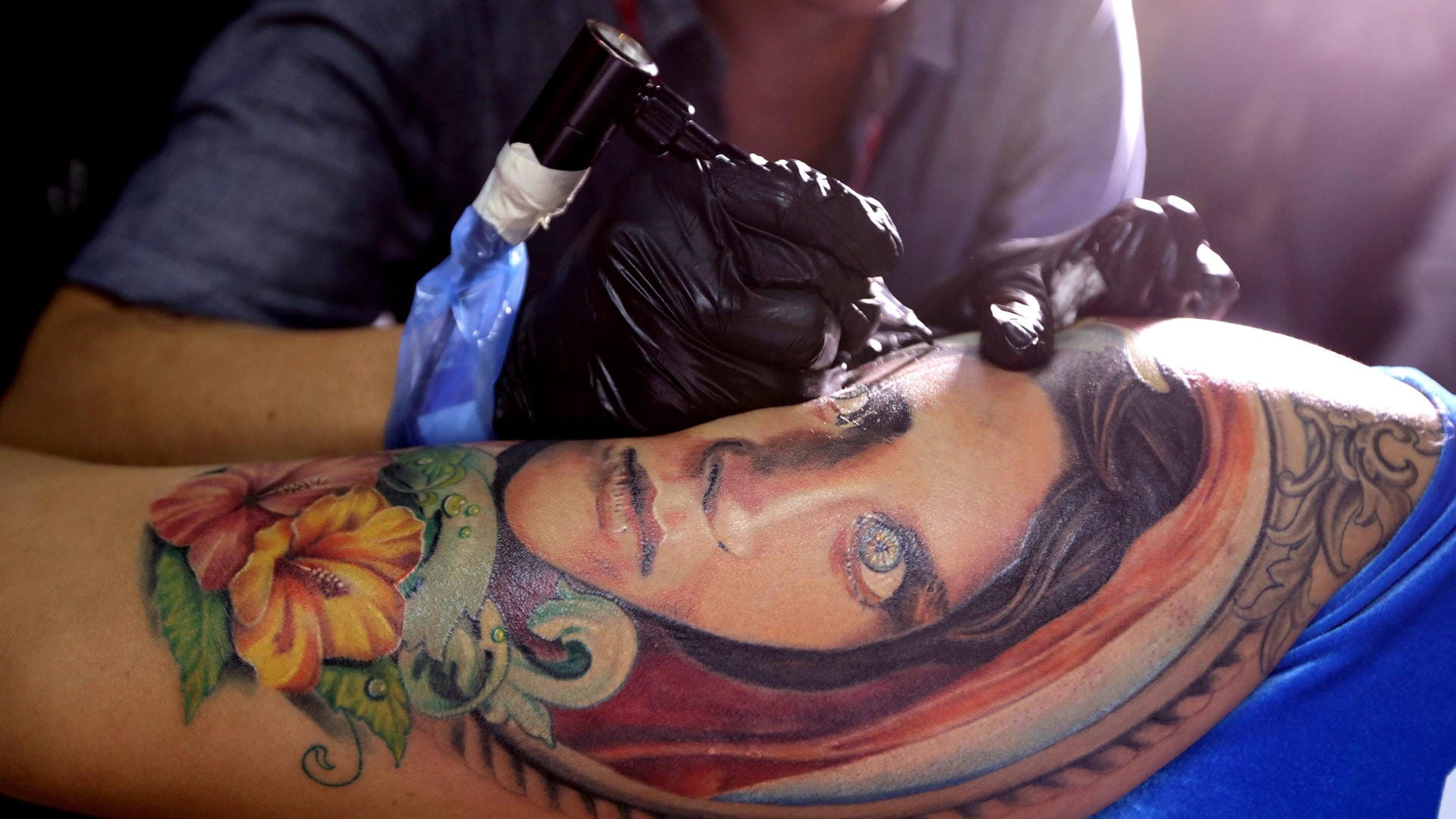 Ein Tätowierer sticht einer Kundin auf der First Hanoi International Tattoo Convention ein Tattoo. Ein Tätowierer sticht einer Kundin auf der First Hanoi International Tattoo Convention ein Tattoo.