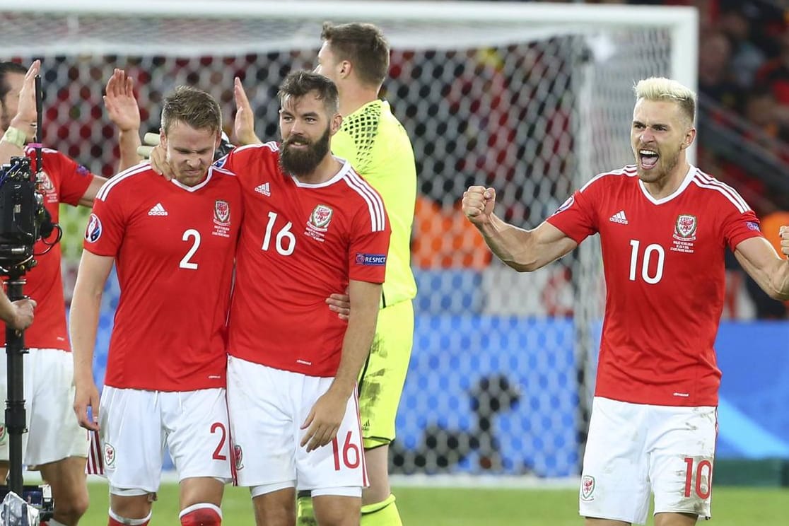 Die beiden Waliser Chris Gunter und Joe Ledley (v.li.) feiern mit Teamkollege Aaron Ramsey (re.) den Sieg gegen Belgien.