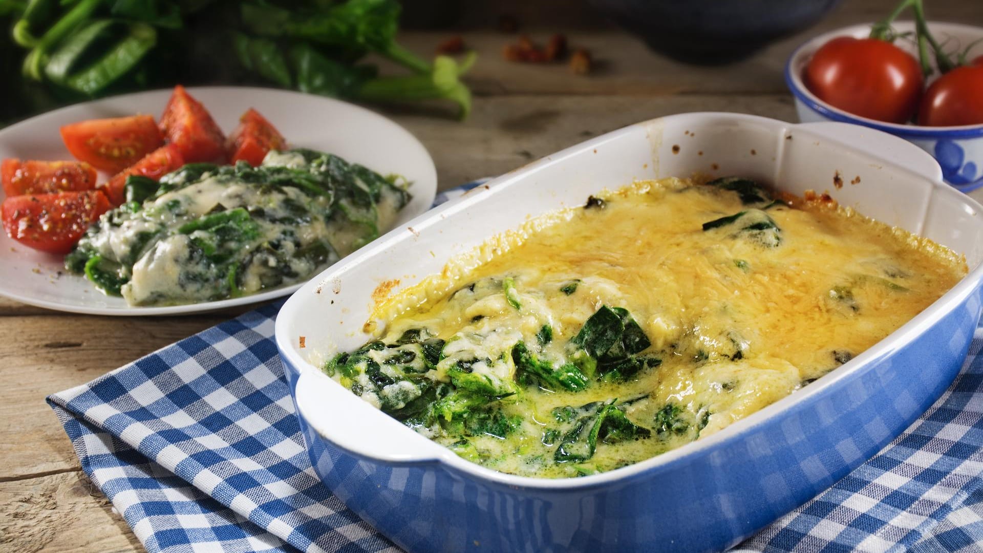 Kartoffel-Spinat-Auflauf in fleischloser Variante zusammen mit frischen Tomaten.