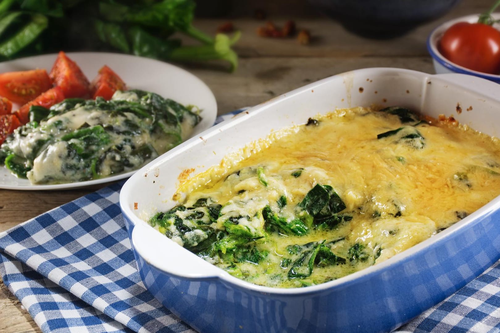 Kartoffel-Spinat-Auflauf in fleischloser Variante zusammen mit frischen Tomaten.