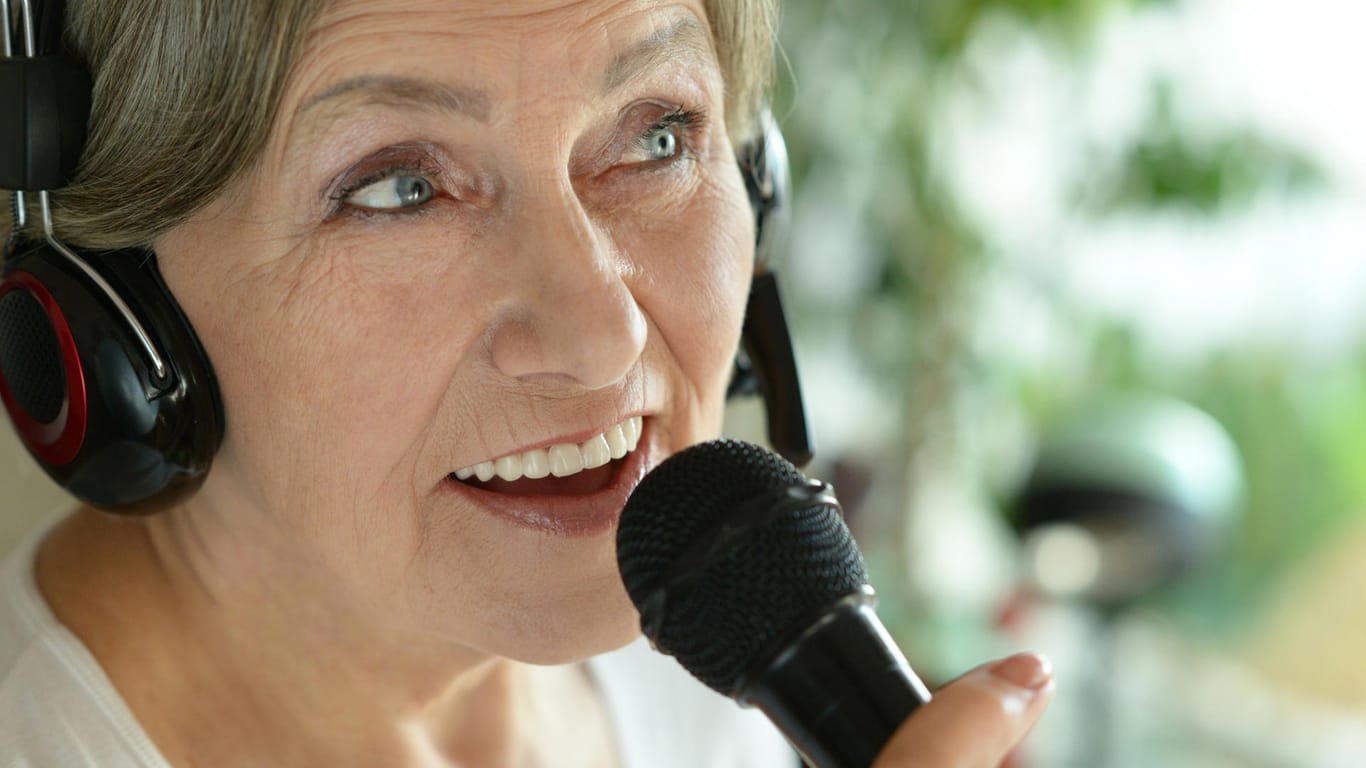 Eine ältere Frau singt in ein Mikrofon.