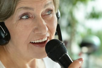 Eine ältere Frau singt in ein Mikrofon.