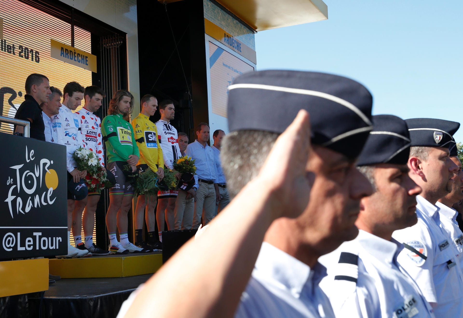 Gedenkminute: Diese Polizisten salutierten zu Ehren der Anschlagsopfer von Nizza. Im Hintergrund das Podium der Tour mit den derzeit Führenden.