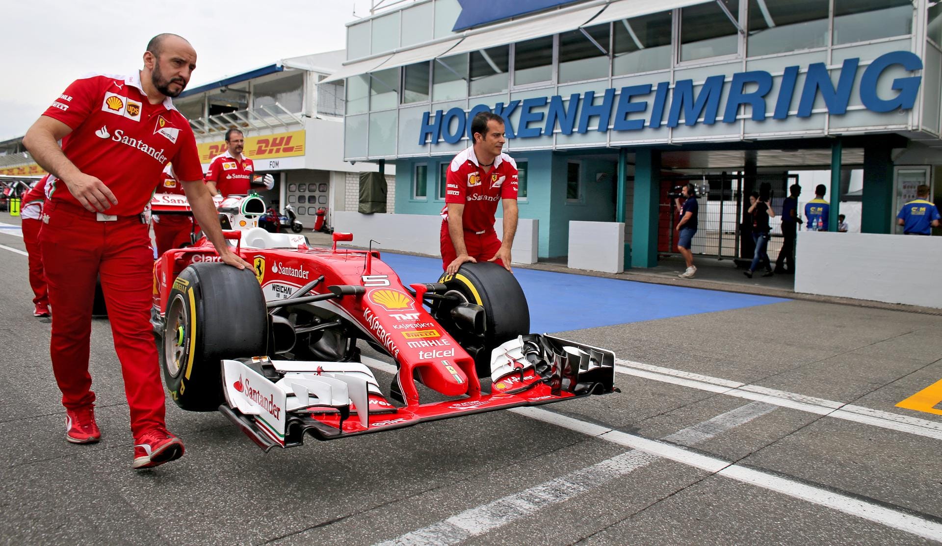 Techniker schieben das Auto von Kimi Räikkönen zur FIA-Abnahme. Oder schwebt der Ferrari dahin?