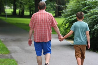 Mario Weinrich und sein 11-jähriger Sohn Leonard laufen im Kurpark von Bad Wörishofen Hand in Hand und genießen ihren Kuraufenthalt.