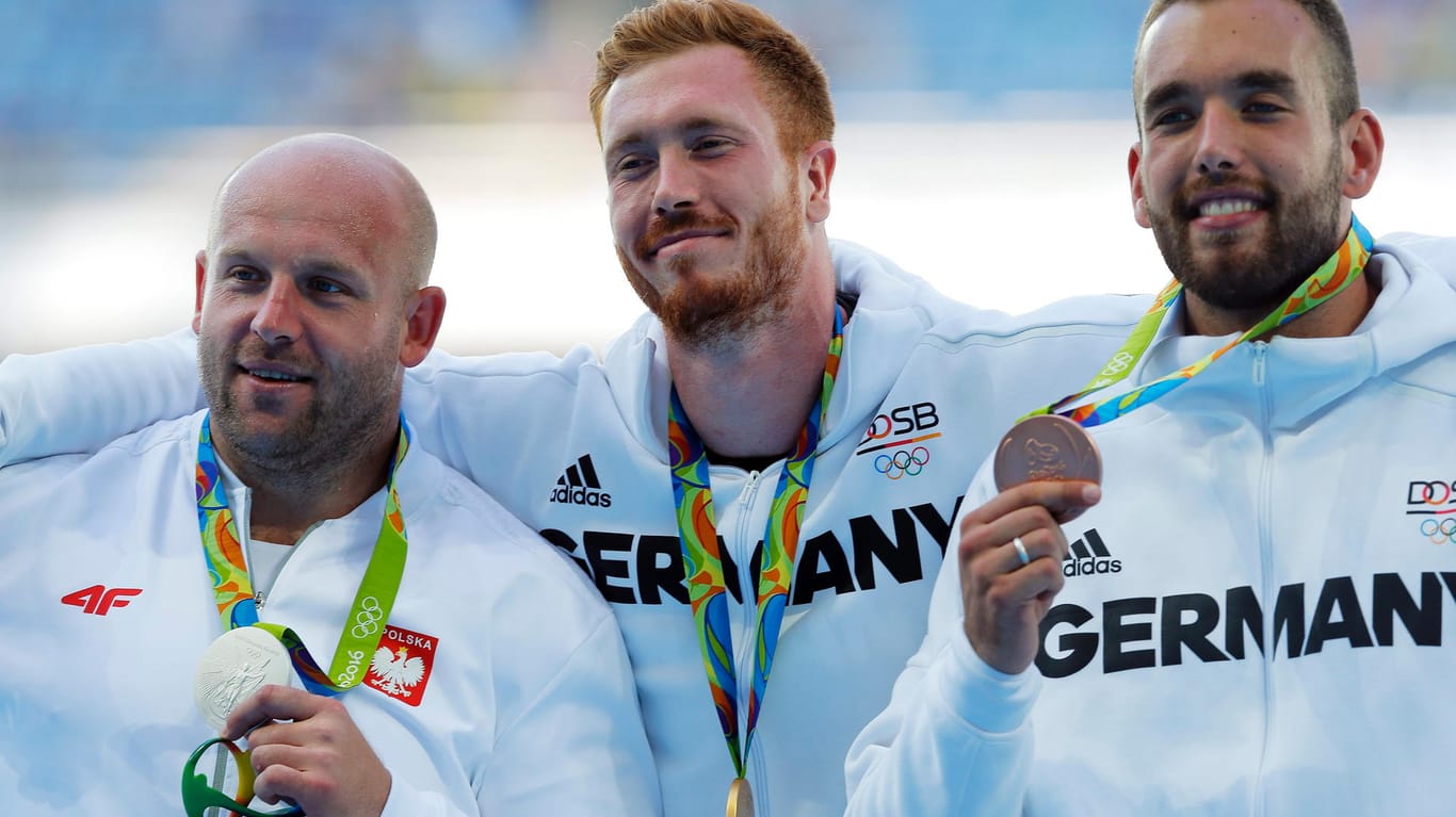 Christoph Harting (Mitte) feiert den Olympiasieg auf seine ganz eigene Weise.