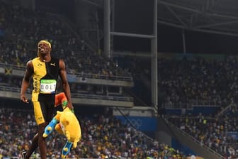 Mit Maskottchen unter dem Arm dreht Usain Bolt nach seinem Sieg eine Ehrenrunde.