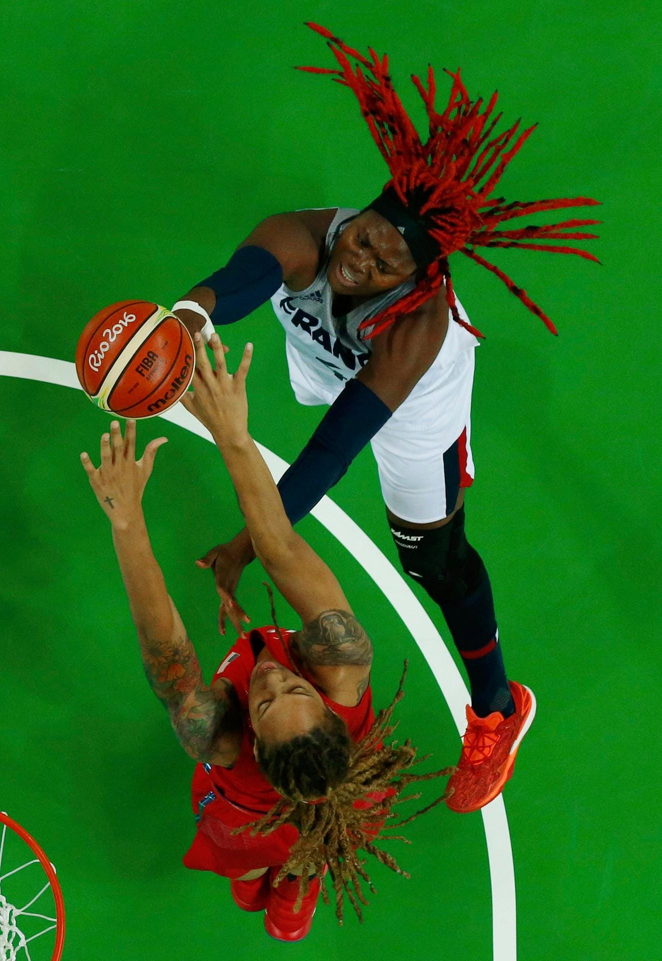 Mit wehenden Haaren kämpfen die beiden Basketballerinnen Isabelle Yacoubou aus Frankreich (re., weiße Spielkleidung) und die Amerikanerin Brittney Griner (li., rote Spielkleidung) im olympischen Halbfinale um den Ball.