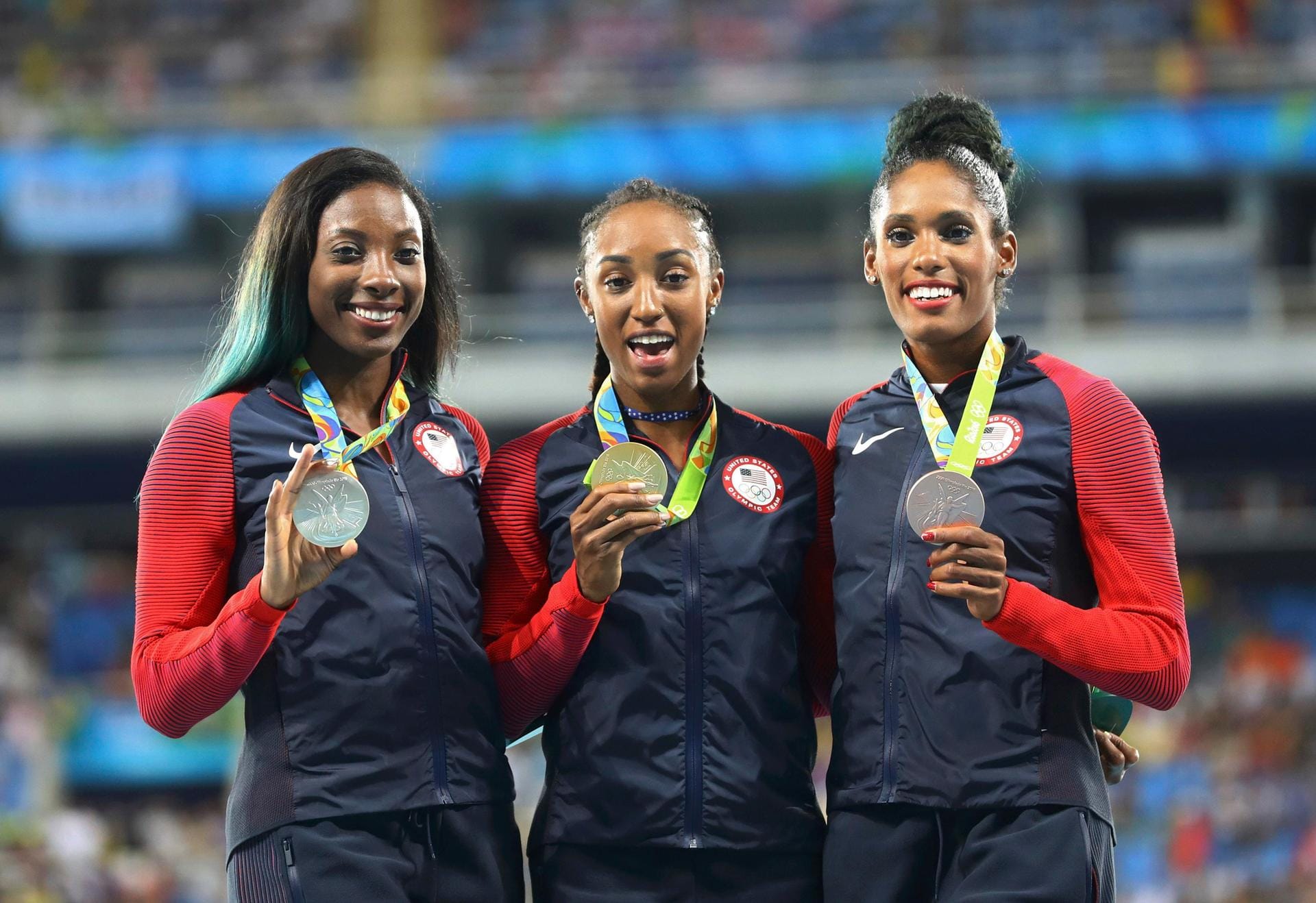 Bitte lächeln! Sichtlich zufrieden zeigen sich die neue Olympiasiegerin Brianna Rollins (Mitte), die Zweite Nia Ali (li.) und die Dritte Kristl Castlin (re.) mit ihren Medaillen auf dem Podium. Gestern Nacht setzten sich die drei US-Damen über 100 Meter Hürden durch und sorgten dafür, dass Gold, Silber und Bronze in die Vereinigten Staaten gehen.