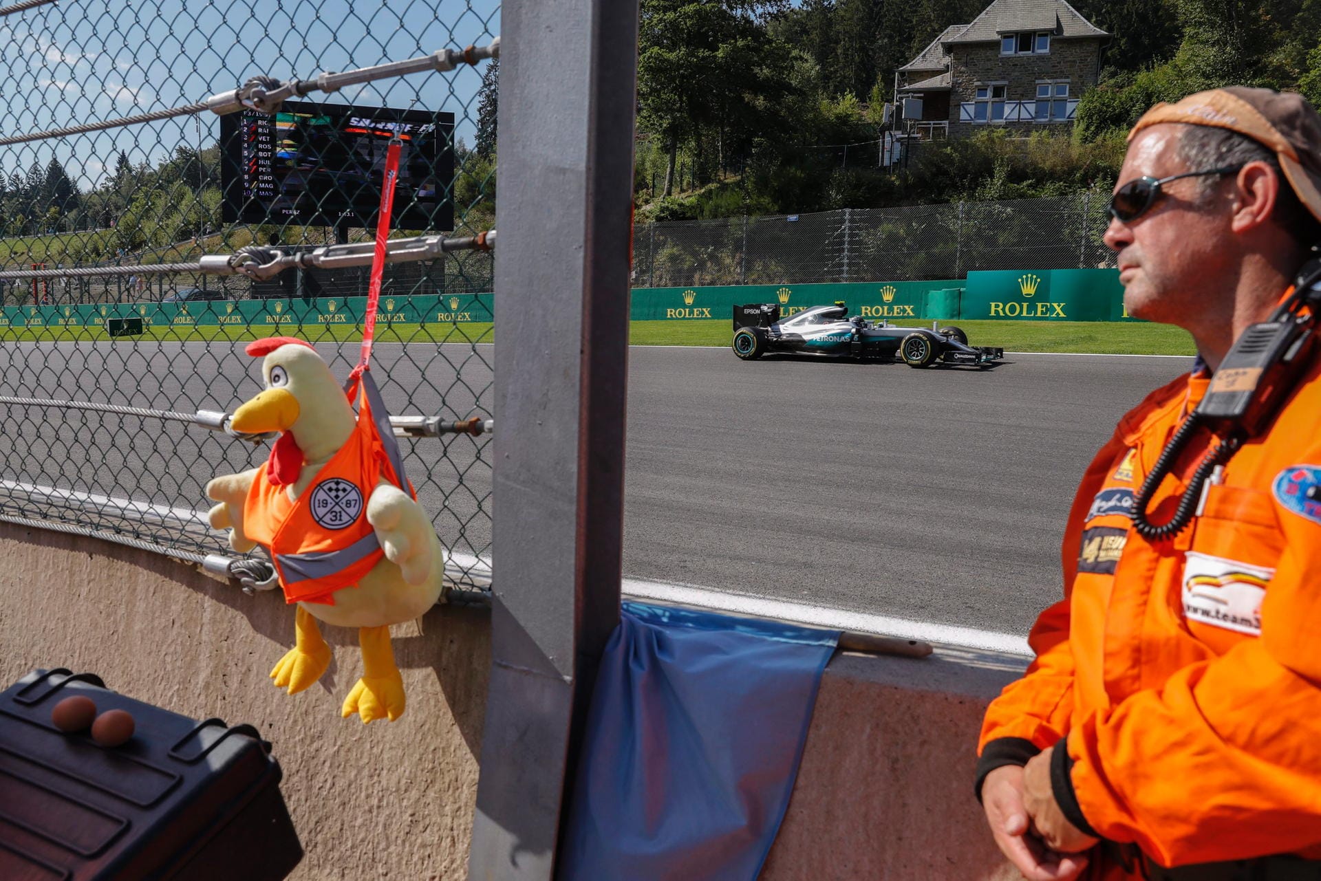 Was hängt denn da am Zaun? Ein Streckenposten plus Maskottchen schauen Nico Rosberg zu.