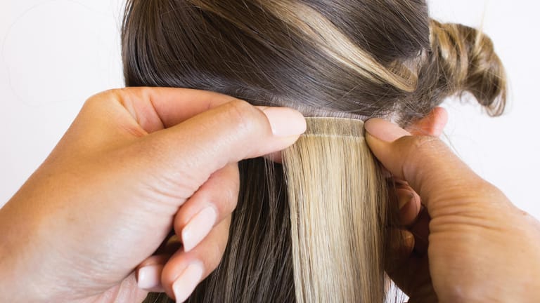 Eine der Methoden für eine Haarverlängerung ist, einzelne Tapes mit speziellen Klebestreifen direkt an der Kopfhaut mit dem eigenen Haar zu verbinden.