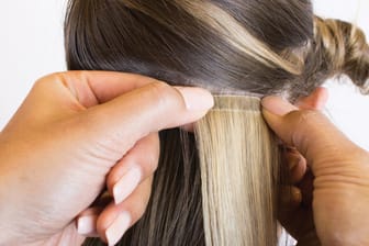 Eine der Methoden für eine Haarverlängerung ist, einzelne Tapes mit speziellen Klebestreifen direkt an der Kopfhaut mit dem eigenen Haar zu verbinden.