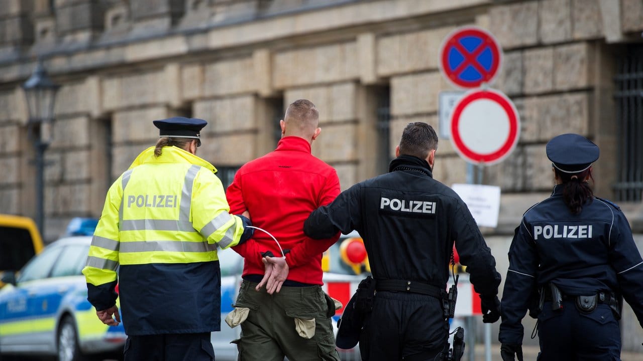 Ein Mann wird von Polizisten abgeführt. Ein Mann wird von Polizisten abgeführt.