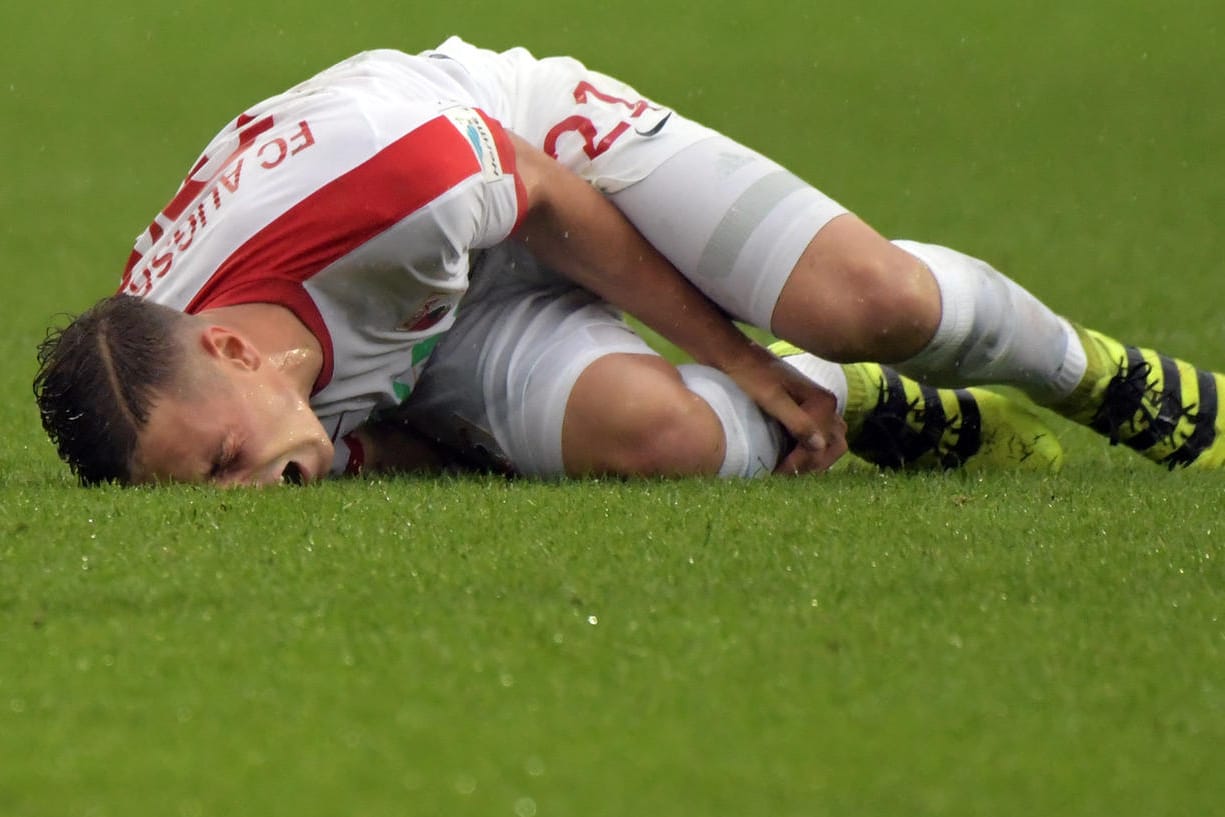 Der Augsburger Dominik Kohr krümmt sich nach dem Foul von José Rodriguez vor Schmerzen auf dem Boden.