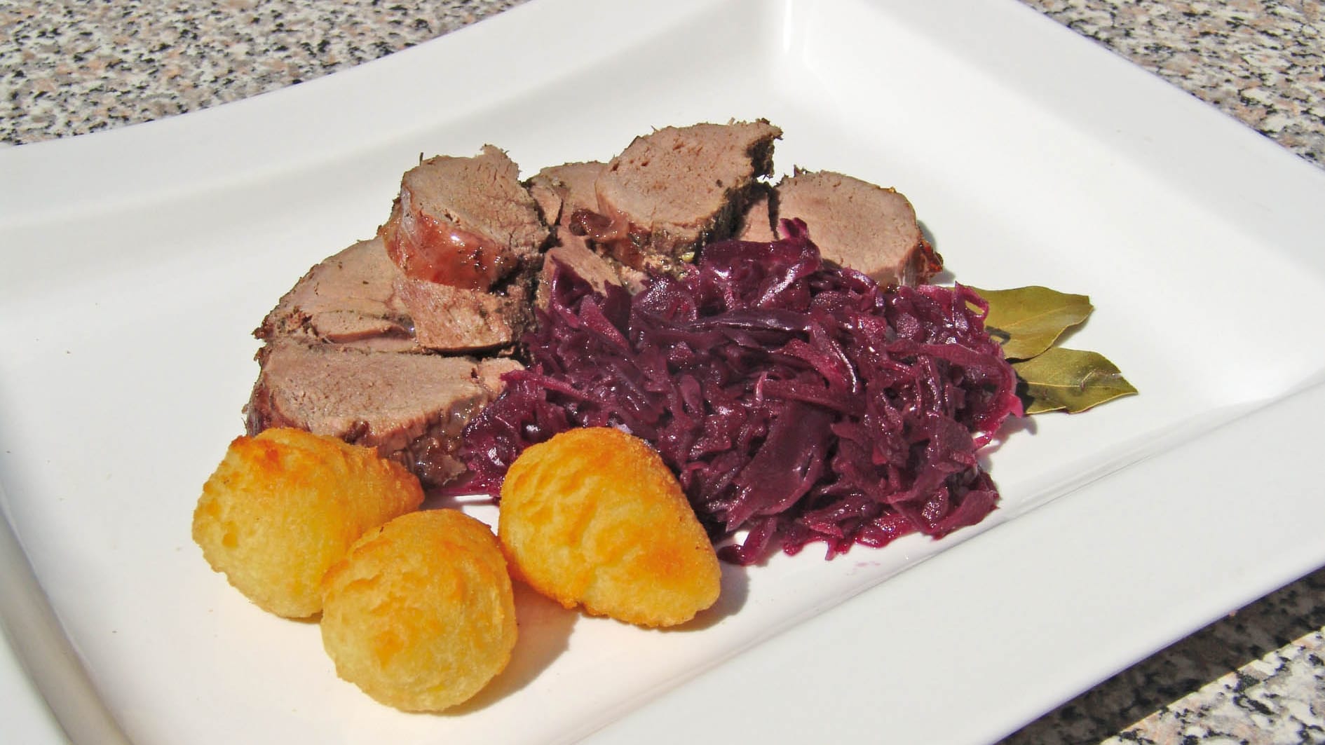 Rehrücken lässt sich nicht nur schmoren, sondern auch grillen – hier mit Rotkohl und Kartoffelrösti.