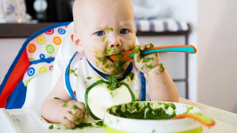 Kleinkind isst Spinat: Veganer verzichten bei der Ernährung auf Fleisch und tierische Produkte.