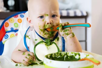 Kleinkind isst Spinat: Veganer verzichten bei der Ernährung auf Fleisch und tierische Produkte.