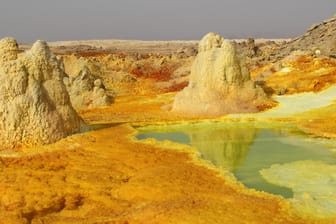 Anblicke wie nicht von dieser Welt: Der abgelagerte Schwefel der Dallol-Senke schimmert in Gelbschattierungen, aus weißen Salztürmen brodelt Wasser hervor.