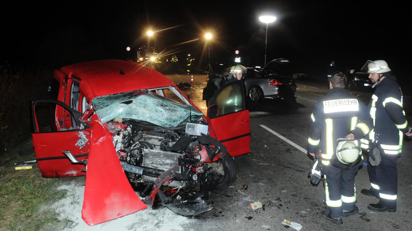Feuerwehrleute stehen bei Mössingen neben einem zerstörten Auto an der Unfallstelle.