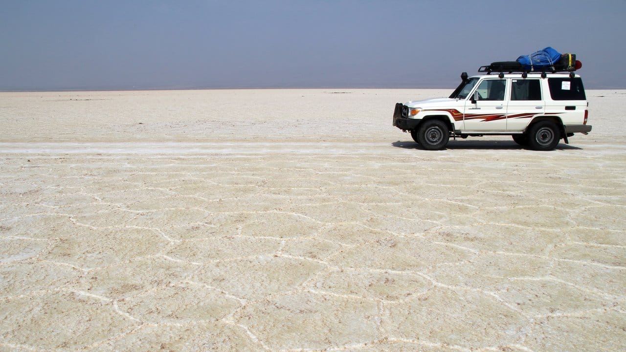 Die Jeeps der Tourgruppen fahren über die flache Salzpfanne der Dallol-Senke in der nordäthiopischen Danakil-Wüste.