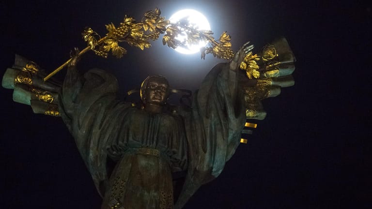 In der ukrainischen Hauptstadt Kiew strahlt der Mond hinter der Statue der Göttin Bereginia auf dem Maidan, dem Unabhängigkeitsplatz.