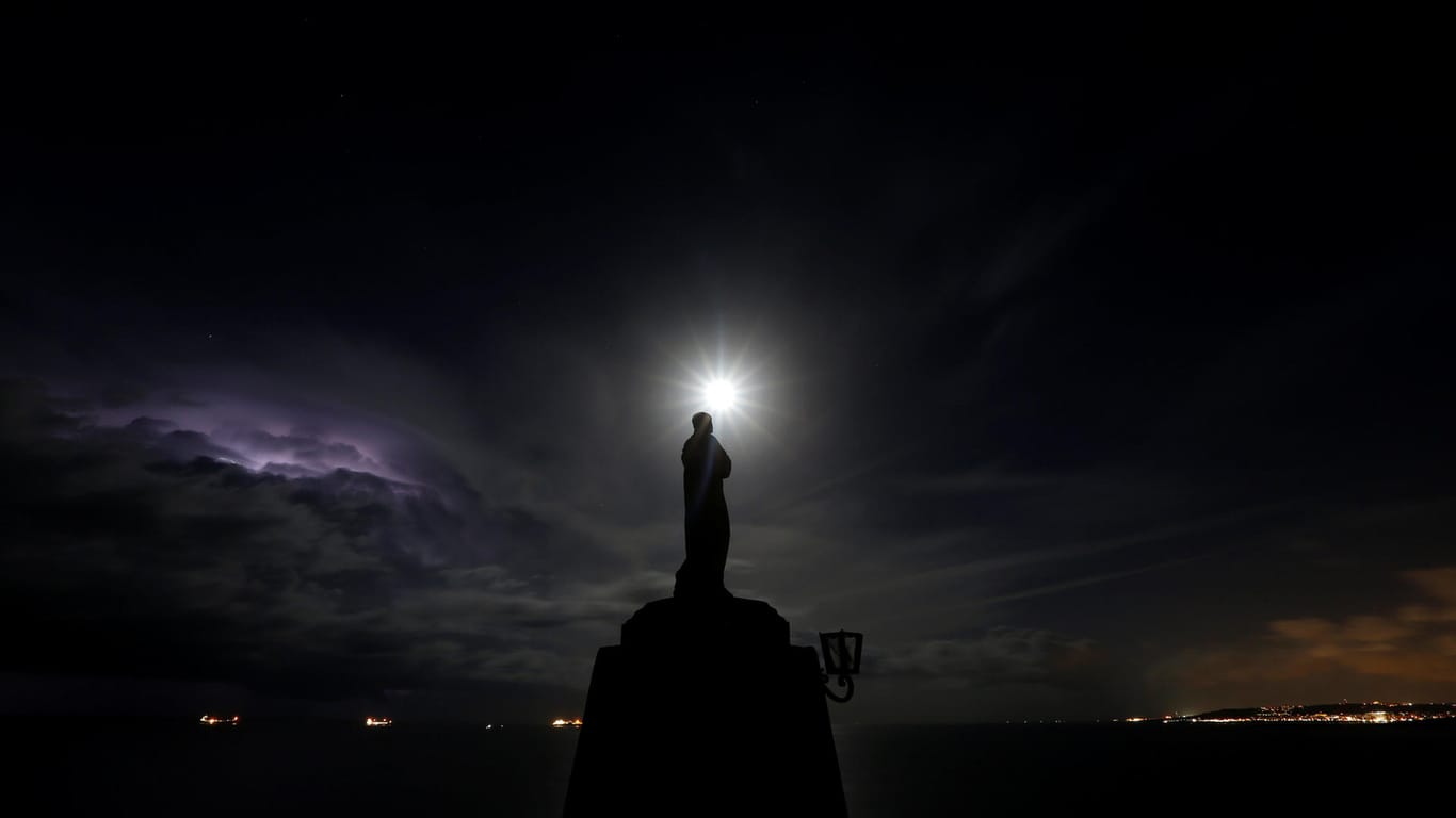 Faszinierendes Himmelsschauspiel im Norden Maltas: Über einer Madonnenstatue leuchtet der Mond, daneben drohen Blitz und Donner.