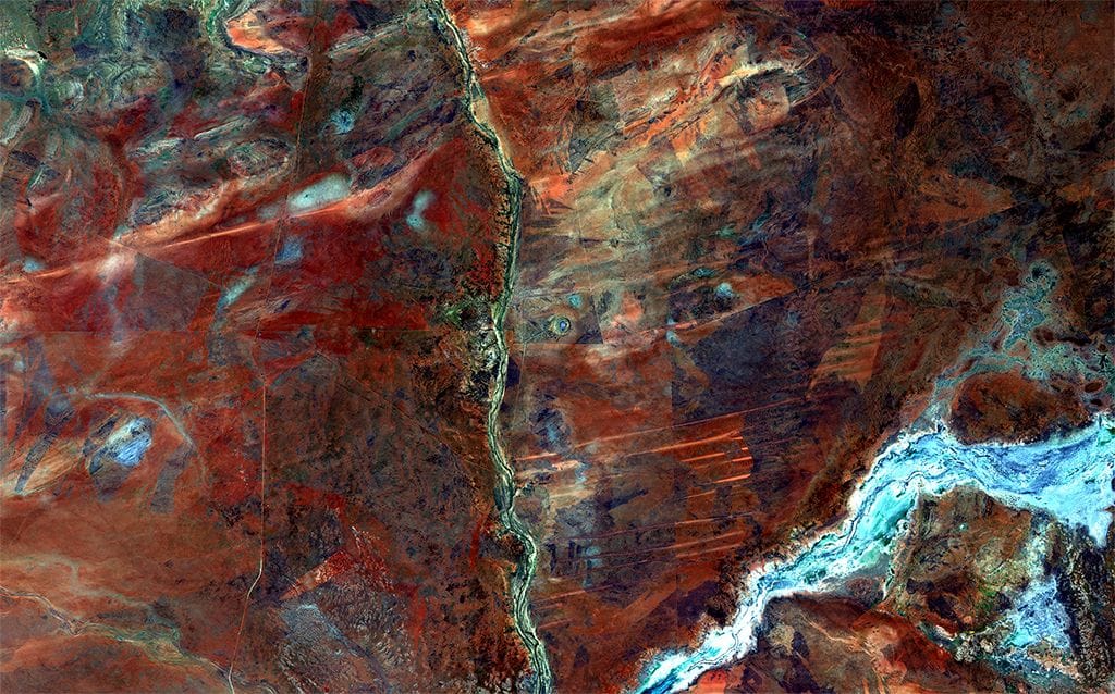 West-Australien, Wolfe Creek National Park: Genau in der Mitte dieser Satellitenaufnahme befindet sich ein Krater, der vermutlich vor 300.000 Jahren entstand, als ein Meteorit einschlug. Die Aborigines sehen in dem 875 Meter breiten Loch den Ausgang einer regenbogenfarbenen Schlange, die den naheliegenden Fluss schuf.