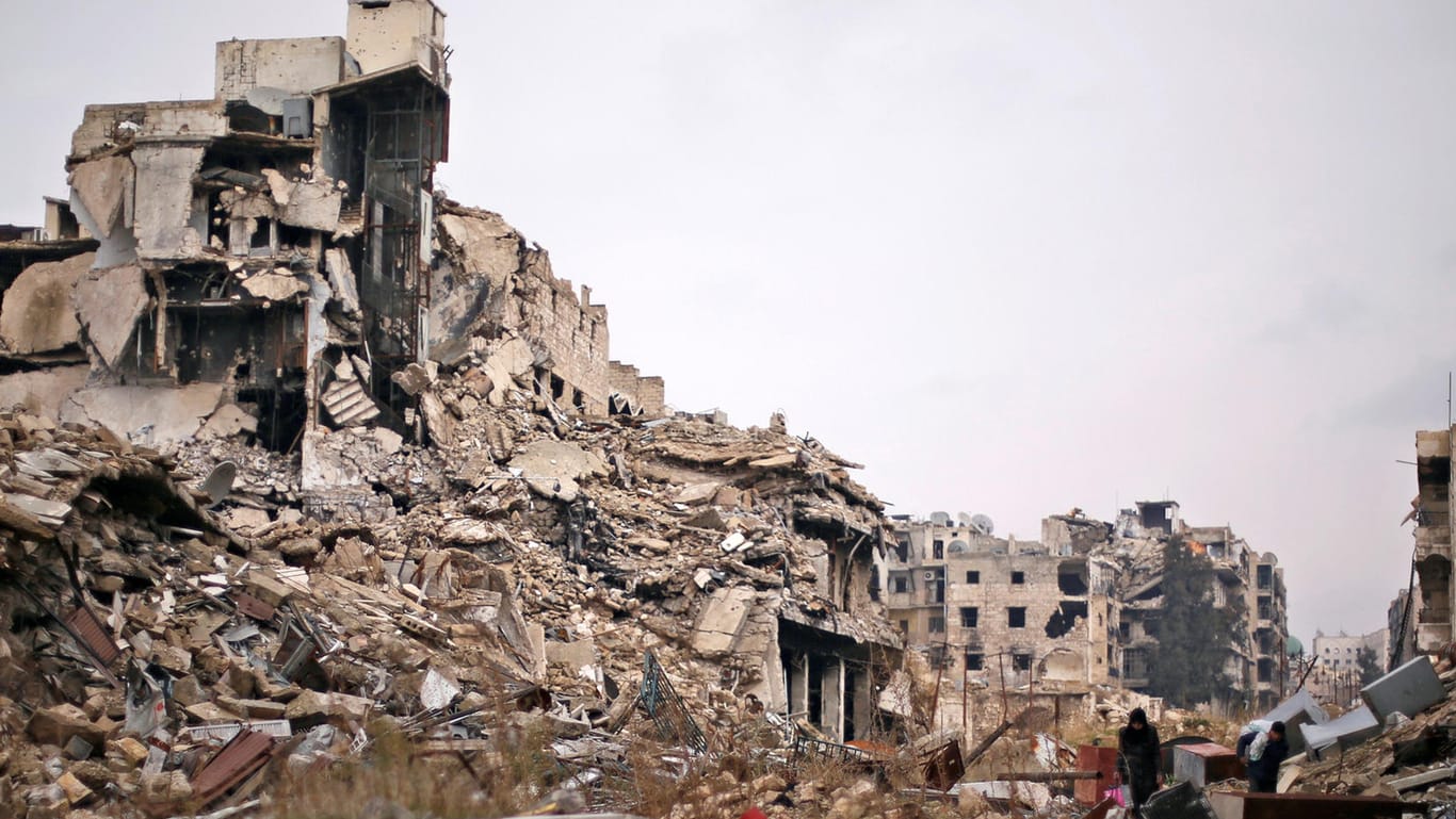 Mensche tragen ihr Hab und Gut aus den völlig zerstörten Gebäuden in Aleppo.