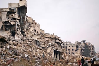 Mensche tragen ihr Hab und Gut aus den völlig zerstörten Gebäuden in Aleppo.