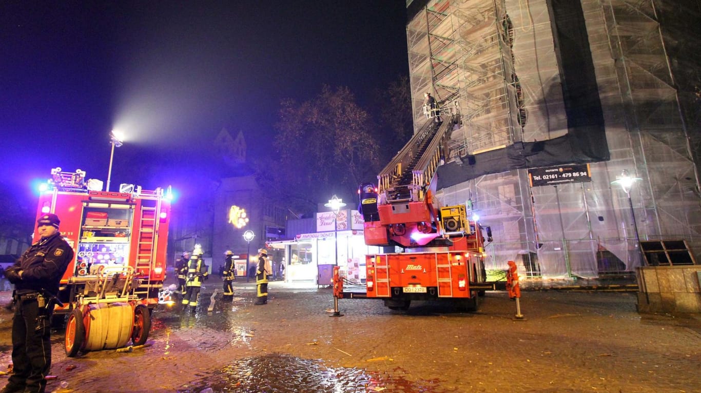 Einsatzkräfte der Feuerwehr stehen in der Silvesternacht vor dem Baugerüst an der Reinoldikirche in Dortmund in dem sich eine Silvesterrakete verfangen hat.