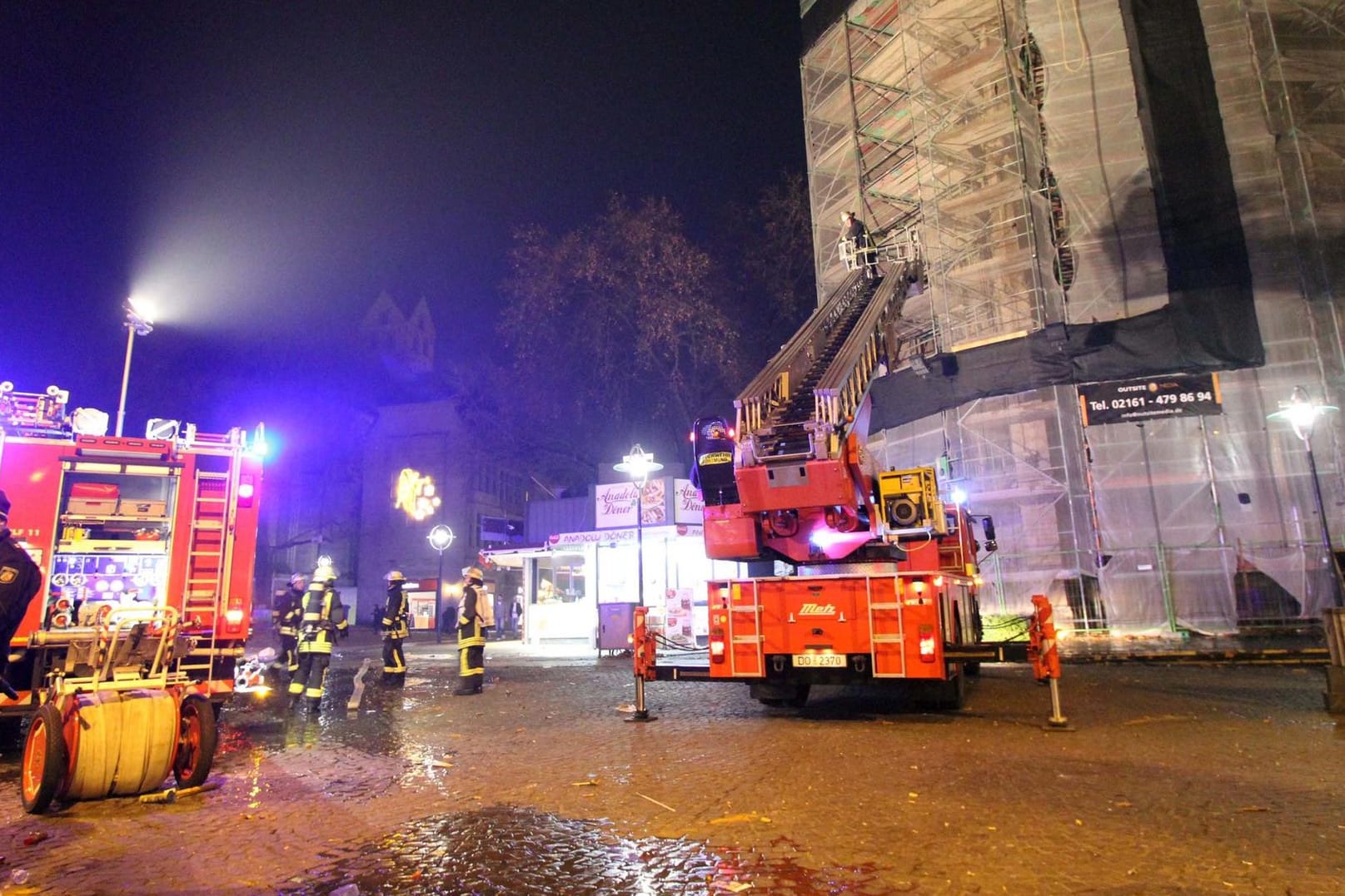 Einsatzkräfte der Feuerwehr stehen in der Silvesternacht vor dem Baugerüst an der Reinoldikirche in Dortmund in dem sich eine Silvesterrakete verfangen hat.