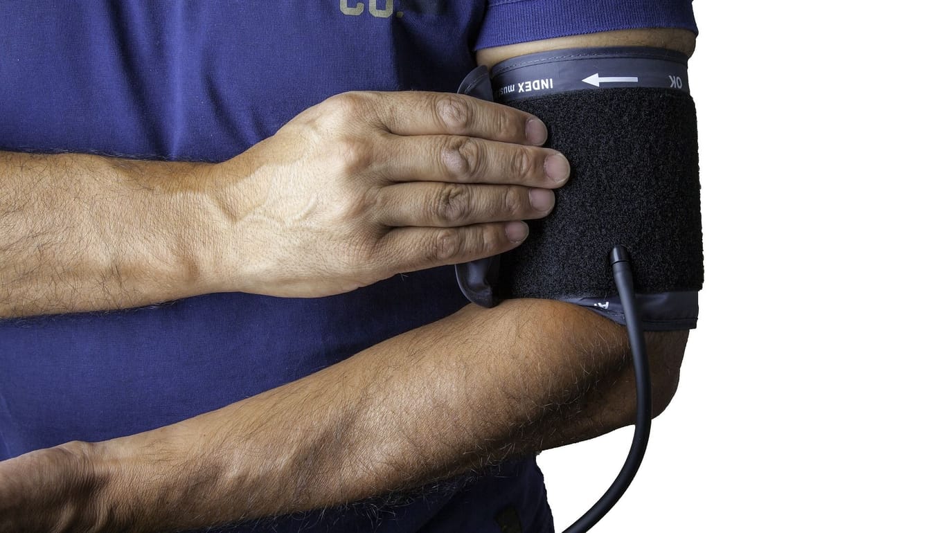 Männerhand hält ein Blutdruckmessgerät am Oberarm