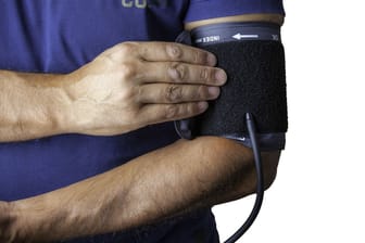 Männerhand hält ein Blutdruckmessgerät am Oberarm