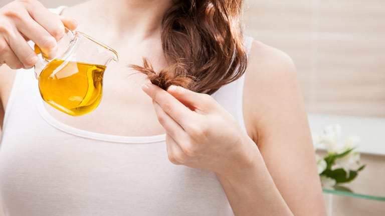 Eine Frau pflegt ihre Haarspitzen mit Öl