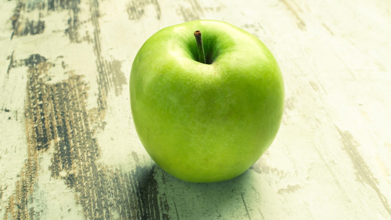 Ein grüner Apfel liegt auf einem Tisch.